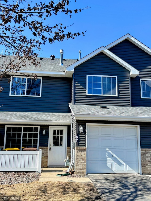 view of front of home with driveway, a shingled roof, and an attached garage