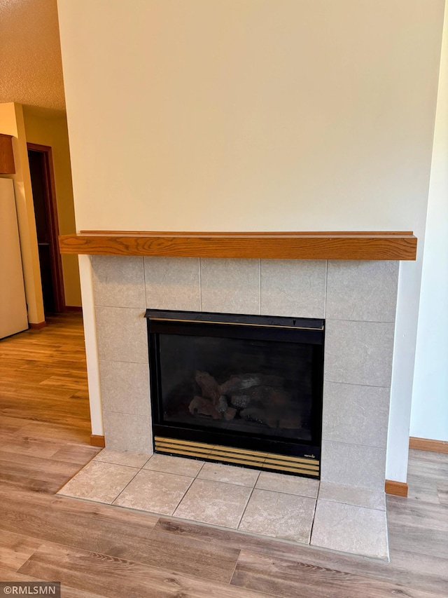 details with wood finished floors, a tile fireplace, and freestanding refrigerator