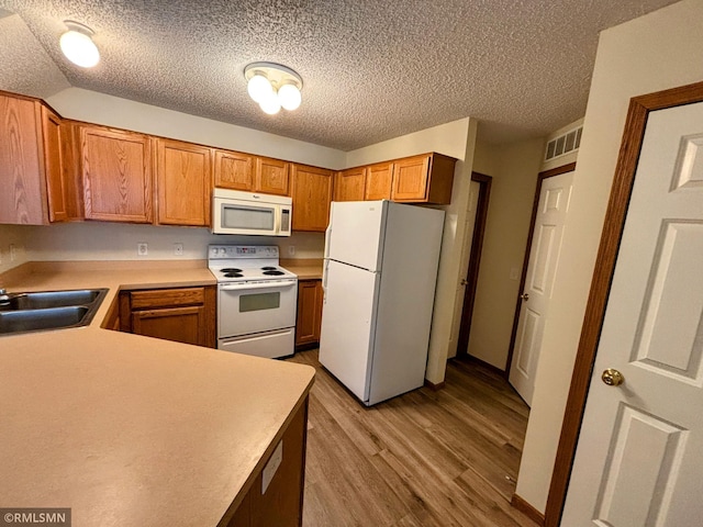 kitchen with white appliances, visible vents, brown cabinetry, light countertops, and light wood-type flooring