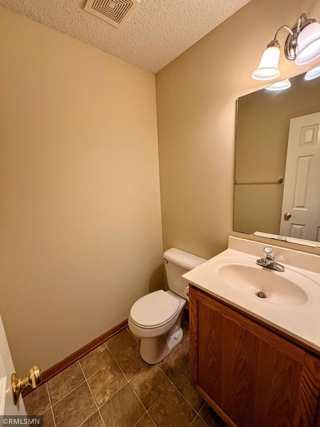 bathroom featuring visible vents, toilet, a textured ceiling, vanity, and baseboards