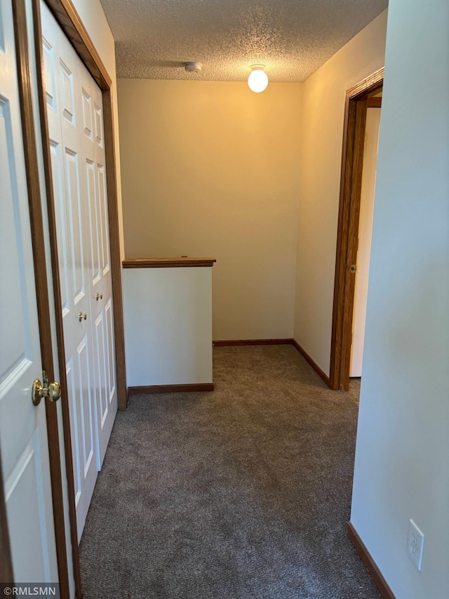 carpeted empty room featuring a textured ceiling and baseboards