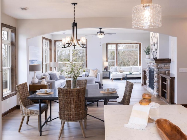 dining area with a notable chandelier, a fireplace, baseboards, and wood finished floors