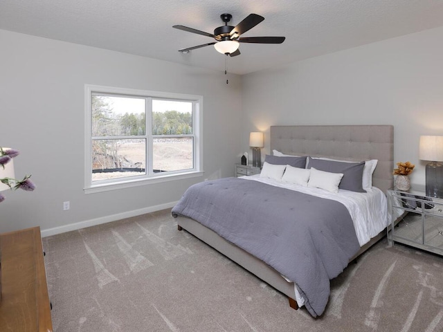 carpeted bedroom featuring a ceiling fan, a textured ceiling, and baseboards