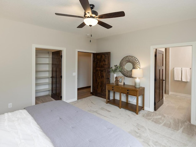 bedroom with light carpet, ceiling fan, ensuite bathroom, and baseboards