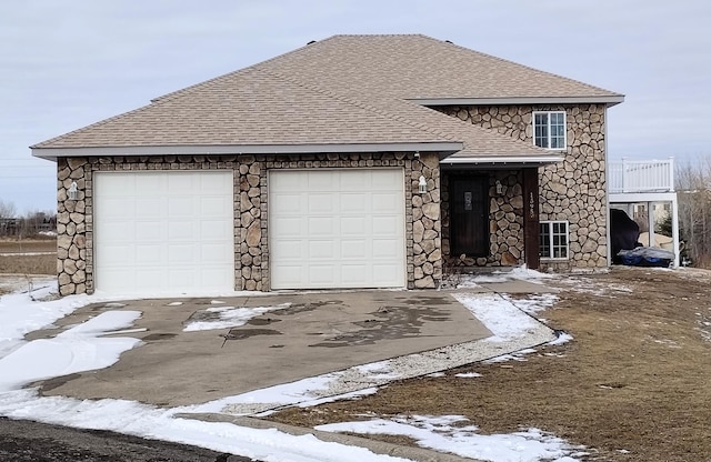 view of front of property with an attached garage, stone siding, a shingled roof, and concrete driveway