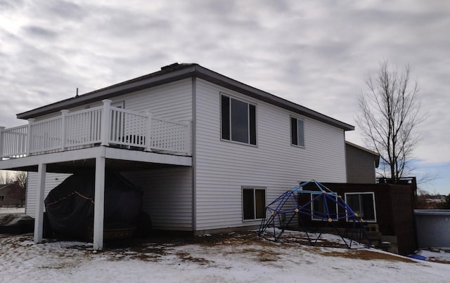 snow covered rear of property featuring a deck