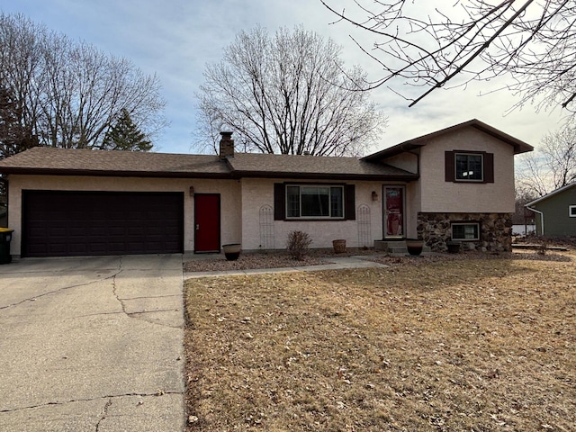 tri-level home featuring stucco siding, an attached garage, a chimney, and driveway