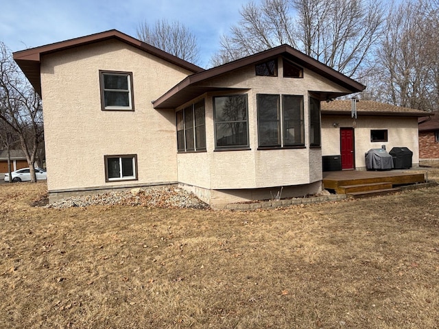 rear view of property with stucco siding and a yard