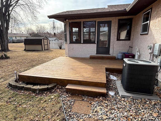 wooden terrace featuring a storage shed, an outbuilding, fence, and central AC