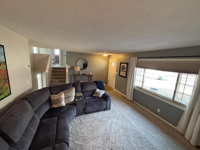 living room with a textured ceiling, stairway, baseboards, and light carpet