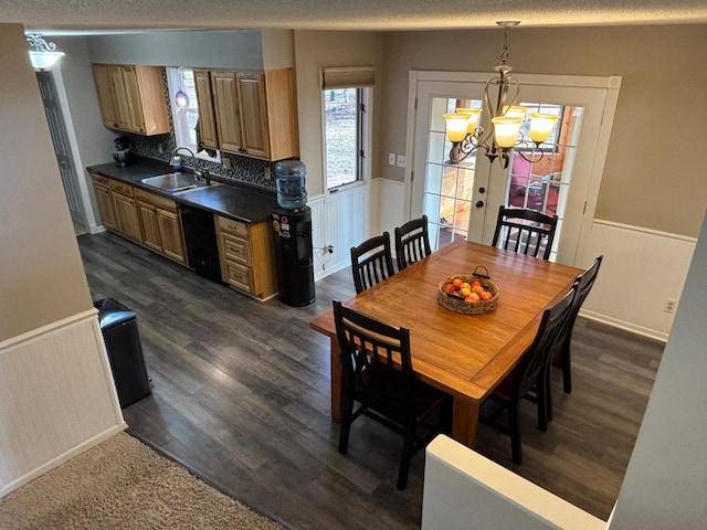 dining space featuring dark wood-style floors, a wainscoted wall, and an inviting chandelier