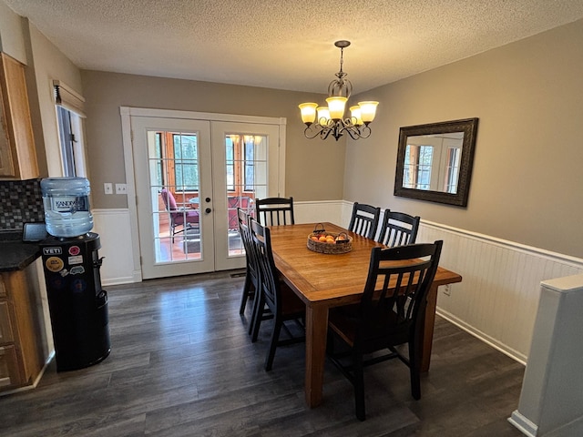 dining room featuring dark wood finished floors, wainscoting, french doors, and a textured ceiling