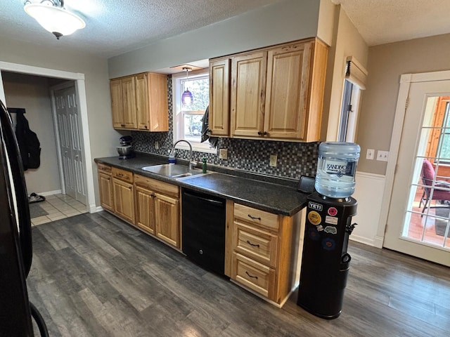 kitchen featuring a sink, dark countertops, dishwasher, and dark wood finished floors