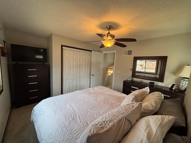 carpeted bedroom featuring visible vents, a textured ceiling, a closet, and a ceiling fan