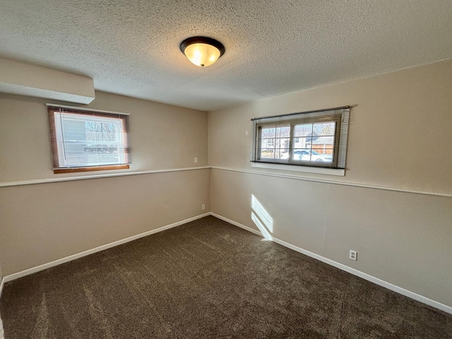 spare room featuring carpet, baseboards, and a textured ceiling