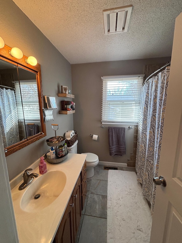 full bath featuring vanity, toilet, visible vents, and a textured ceiling