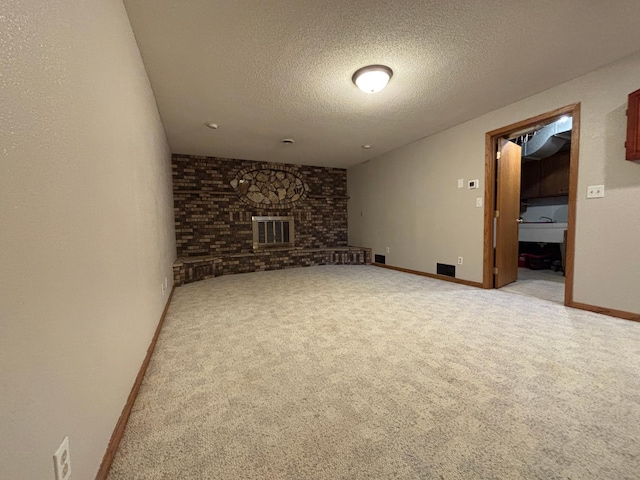 unfurnished living room with a brick fireplace, carpet flooring, visible vents, and a textured ceiling