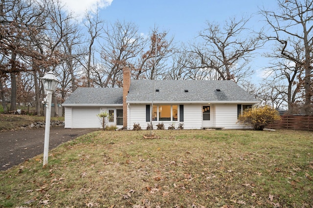 view of front of house with an attached garage, fence, driveway, roof with shingles, and a front lawn