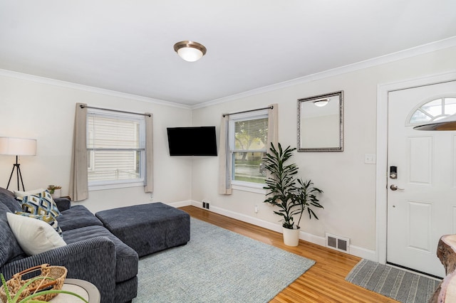 living room with wood finished floors, crown molding, and baseboards