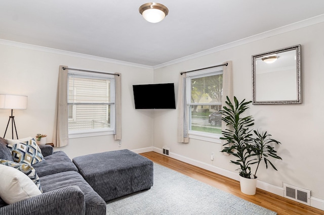 living room with wood finished floors, ornamental molding, plenty of natural light, and baseboards