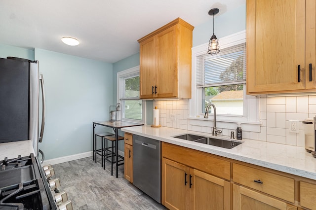 kitchen with a sink, appliances with stainless steel finishes, light wood-style flooring, tasteful backsplash, and plenty of natural light