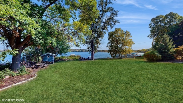 view of yard featuring a water view, a shed, and an outbuilding