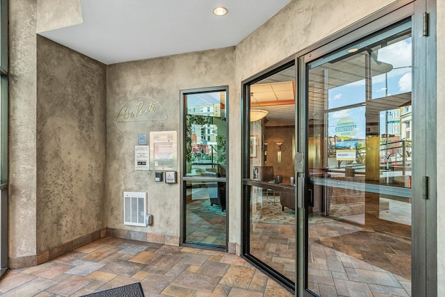 doorway with baseboards, visible vents, and stone tile floors