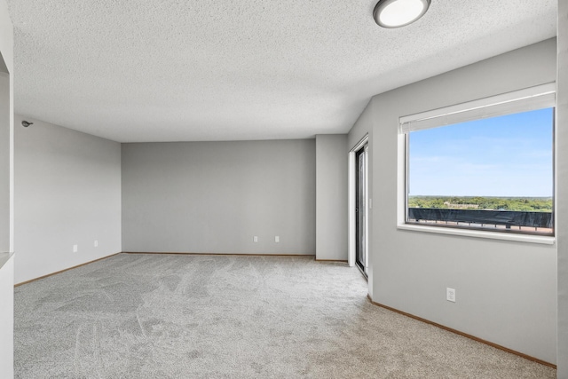 carpeted empty room with baseboards and a textured ceiling