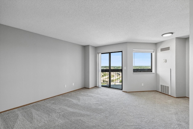 spare room with carpet, visible vents, a textured ceiling, and baseboards