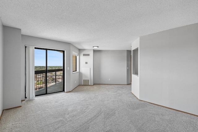 carpeted spare room with visible vents, a textured ceiling, and baseboards