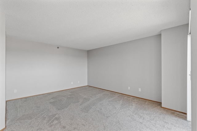 carpeted empty room featuring a textured ceiling and baseboards