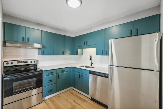 kitchen featuring tasteful backsplash, light wood-style floors, stainless steel appliances, under cabinet range hood, and a sink