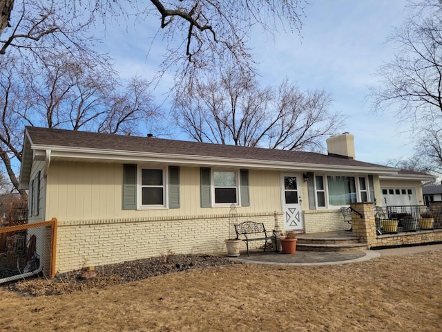 ranch-style house with brick siding, a chimney, a garage, and fence