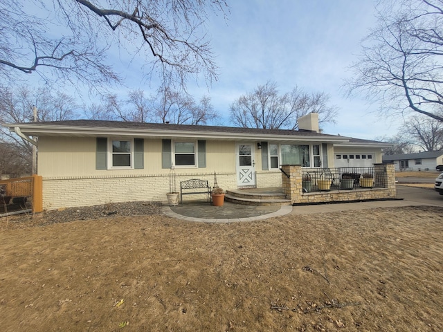 single story home with a garage, brick siding, a chimney, and fence