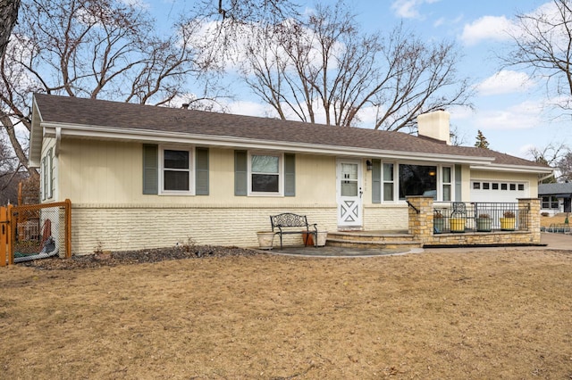 ranch-style house with brick siding, fence, a front yard, a chimney, and an attached garage