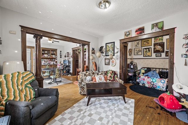 living area with hardwood / wood-style flooring, ornate columns, and a textured ceiling