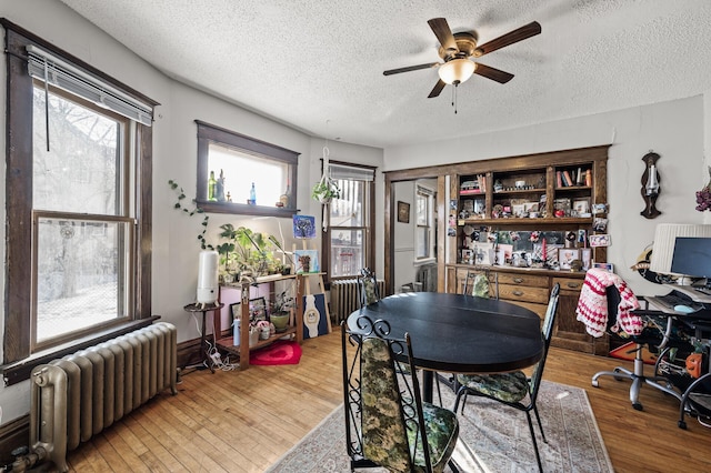 dining space with a textured ceiling, radiator heating unit, a ceiling fan, and hardwood / wood-style floors