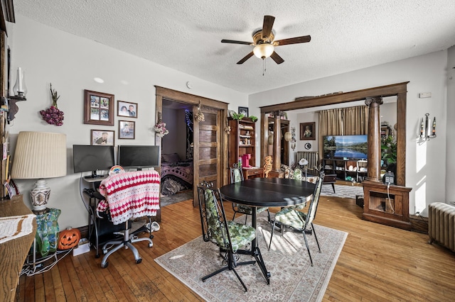 dining room with a textured ceiling, radiator heating unit, a ceiling fan, and hardwood / wood-style floors