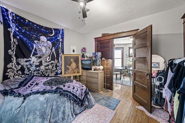 bedroom with a textured ceiling, light wood-type flooring, and ceiling fan