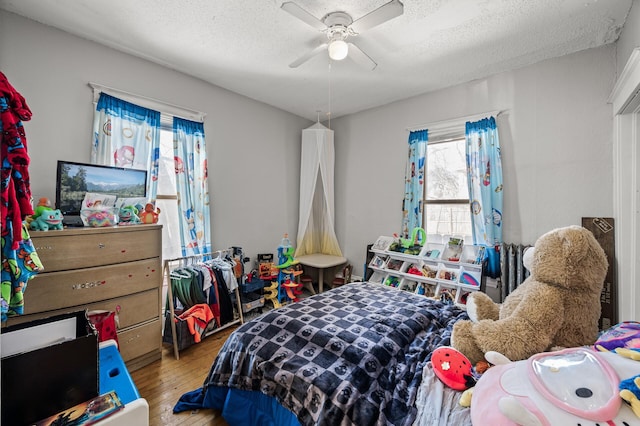 bedroom featuring ceiling fan, wood finished floors, and a textured ceiling