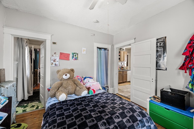 bedroom with a textured ceiling, ceiling fan, and wood finished floors