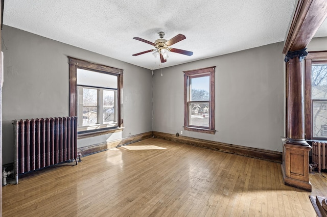 spare room with radiator heating unit, a healthy amount of sunlight, and light wood-style floors