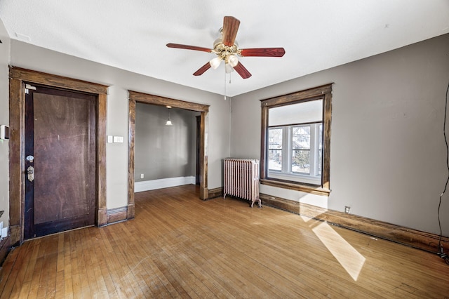 unfurnished bedroom featuring baseboards, a ceiling fan, radiator heating unit, and hardwood / wood-style flooring