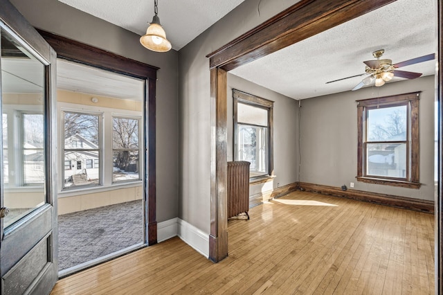 entryway featuring light wood-style flooring, a textured ceiling, radiator heating unit, and baseboards