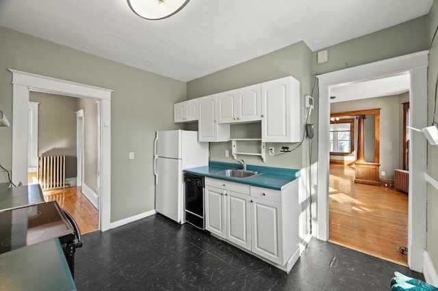 kitchen with black appliances, a sink, radiator heating unit, white cabinetry, and baseboards