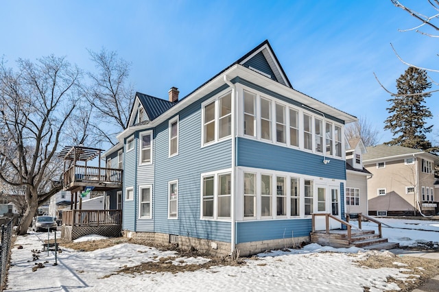 exterior space featuring a wooden deck, a sunroom, and a chimney