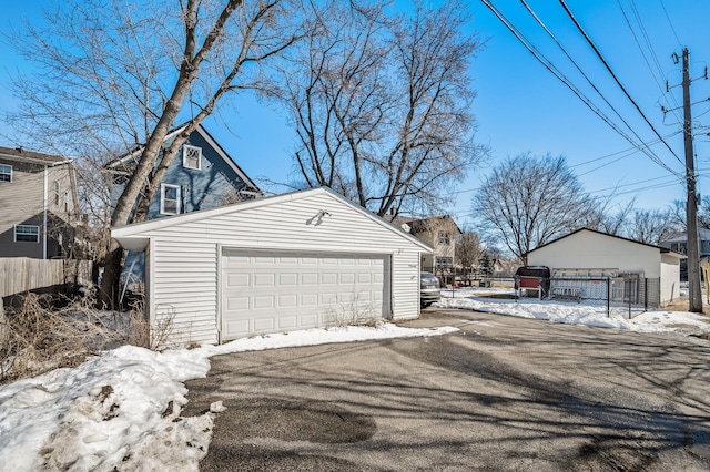 snow covered garage featuring a garage and fence