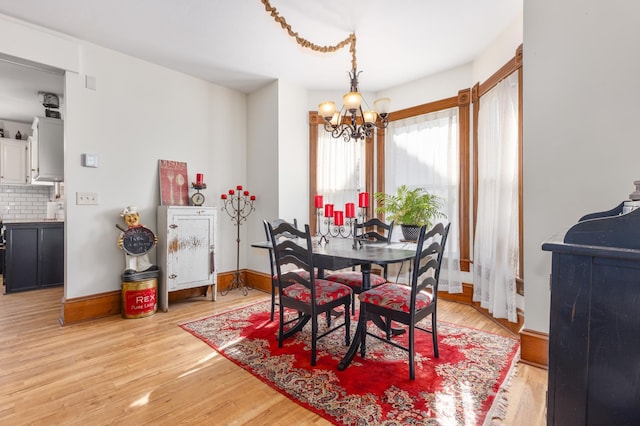 dining space featuring an inviting chandelier, baseboards, and light wood-type flooring