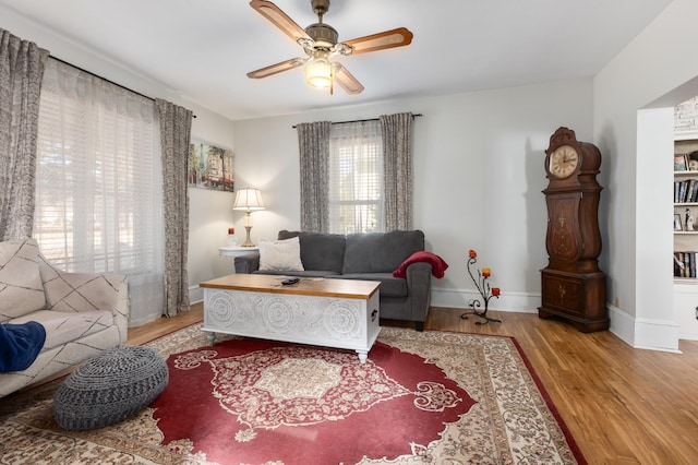 living room with wood finished floors, baseboards, and ceiling fan