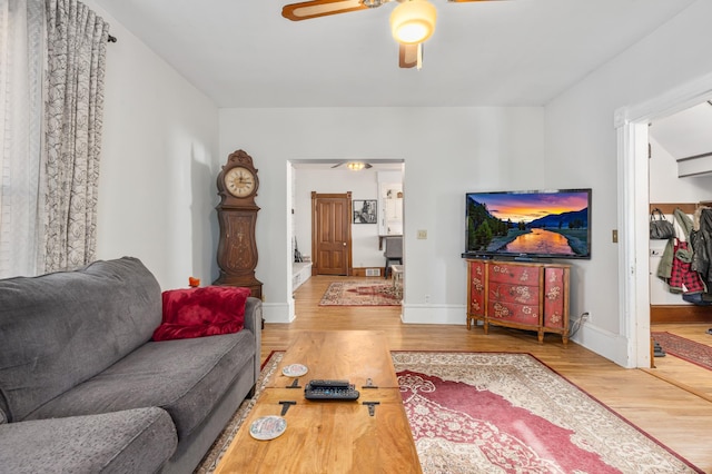 living area featuring baseboards, wood finished floors, and a ceiling fan